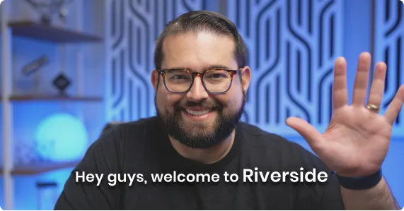Smiling man with glasses waving in front of blue patterned background with text 'Hey guys, welcome to Riverside'.